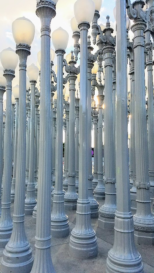 One of the most famous and free (since it is an outdoor sculpture) art you can see in the park at LACMA is the iconic Urban Lights. Created by Chris Burden, it is made of 202 restored street lamps in various styles based on where they were from (most are from southern California and some from Portland Oregon too!). The lamps are painted grey and assembled in a grid, and are solar powered and become lit in the evening.