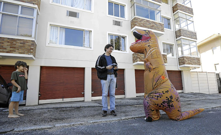 Michelle Roodman, who is brightening up the lockdown for many by dressing in her inflatable T-Rex costume, delivers one of her face masks to Andrew Barkley.