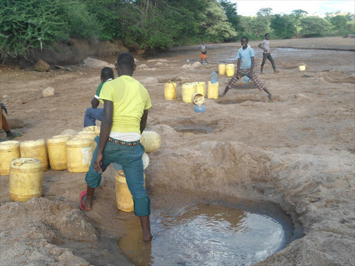 Residents draw water from a river in Mwingi. /FILE