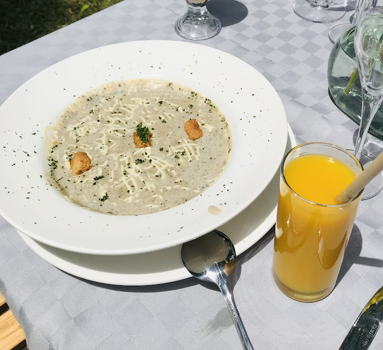 Cream of garlic soup garnished with croutons and ground parsley leaves with a glass of passion juice.