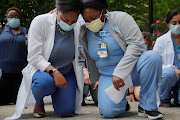 Nurses Sasha Dubois and Farah Fevrin kneel for the 8 minutes and 46 seconds of silence during a vigil at Brigham and Women’s Hospital, where many coronavirus patients have been treated, against the backdrop of the death of George Floyd in Minneapolis police custody, in Boston, Massachusetts on June 5 2020. 