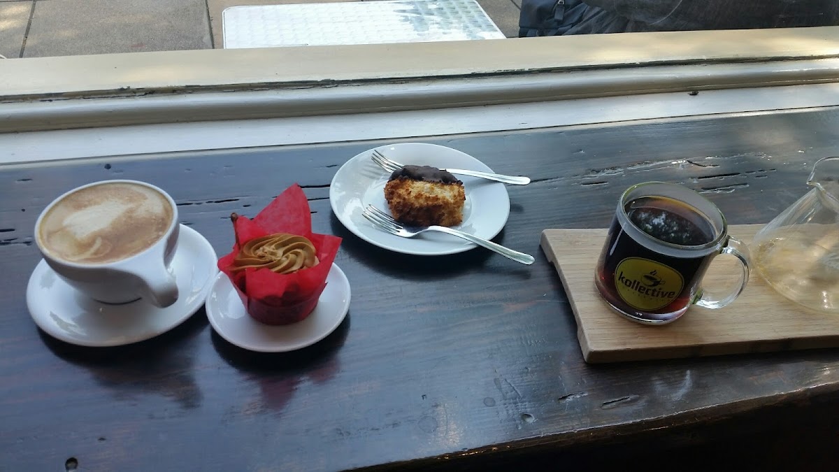 Left to right: white mocha latte, gluten-free carrot cake cupcake w/ molasses frosting, gluten free chocolate dipped macaroon , Ethiopian pour over coffee.