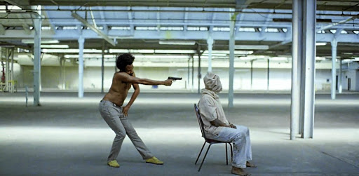 Donald Glover, as Childish Gambino, shoots a hooded man in a screen grab from his music video 'This Is America'.