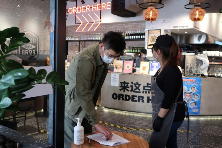 A customer writes down his information as he enters a Moka Bros restaurant in Beijing, China on April 10 2020. Picture: REUTERS/MARTIN POLLARD