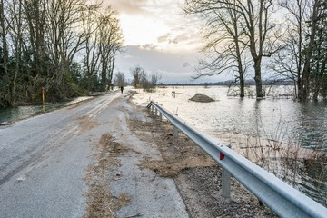 a road that is slightly flooded and has debris from the lake next to it, road hazard theme for motorcyclists in florida