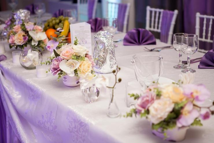 Mesa de casamento com uma série de arranjo de flores brancas e lilás