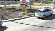 RED FOR DANGER: 
       A motorist waits at a level crossing in White Road during the launch of the CCTV camera system in Retreat, Cape Town, yesterday. The launch was a bid to curb lawlessness at level crossings. 
       Photo supplied by the department of transport