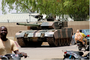 People drive past a Chad army tank near presidential palace, as fighters from the rebel Front for Change and Concord in Chad (FACT) appeared to be moving toward the capital according to the United States, in N'djamena, Chad on April 19 2021. 