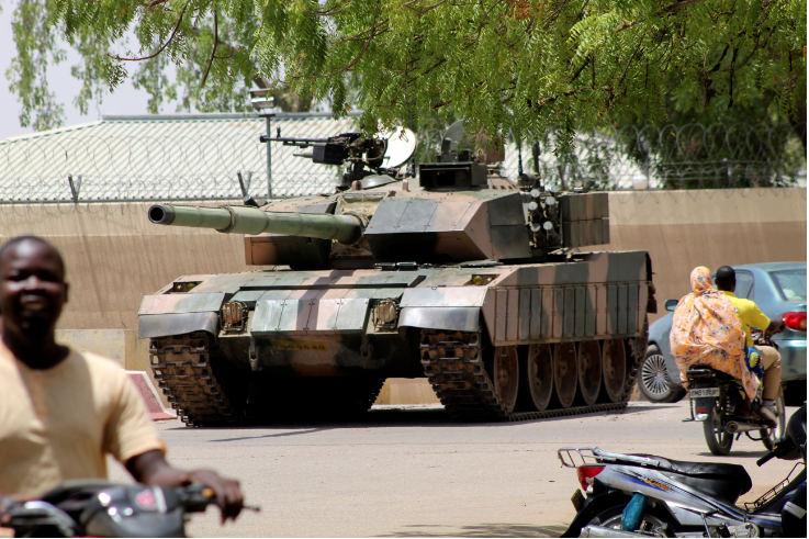 People drive past a Chad army tank near presidential palace, as fighters from the rebel Front for Change and Concord in Chad (FACT) appeared to be moving toward the capital according to the United States, in N'djamena, Chad on April 19 2021.