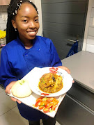 Eugenea Seroka carrying a plate of her winning chicken stew with mini dumplings and salad.