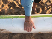 Bryon Machado shows where the Great White shark bit his canoe. 