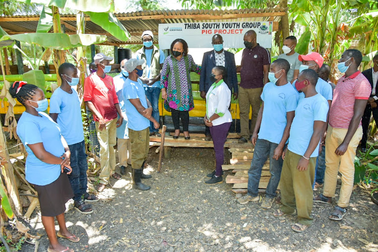 Governor Waiguru and members of a youth group rearing pigs under the Wezesha project in Thiba South, Mwea