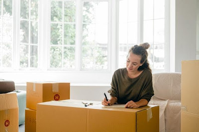 A happy woman packing her moving boxes after learning how downsizing can make us happier