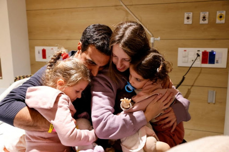 Aviv Asher, 2,5-year-old, her sister Raz Asher, 4,5-year-old, and mother Doron, react as they meet with Yoni, Raz and Aviv's father and Doron's husband, after they returned to Israel to the designated complex at the Schneider Children's Medical Center, during a temporary truce between Hamas and Israel, in Petah Tikva, Israel, in this handout picture released on November 25, 2023.