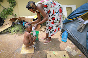 Nanette Kabemba bathes her son next to their tent set up outside the UNHCR office in Pretoria.