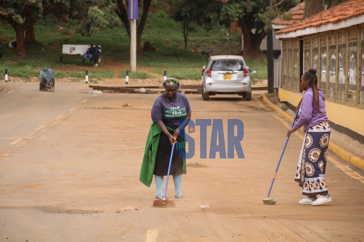 Two women sweeping the entrance of the Green Park Bus terminus May 18, 2022