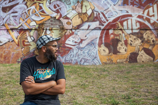 Designer and graffiti artist Quasiem Gamiet in front of the “Cape of Styles” wall in Salt River.