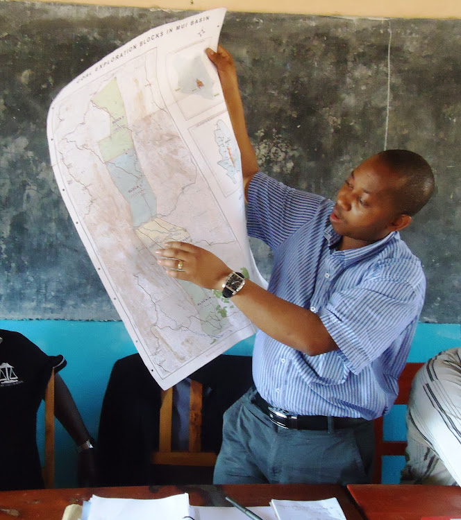 Former chairman of the Mui Coal Basin Blocks C and D community liaison committee Erick Mutua holds a map showing the coal-rich blocks during a public sensitisation meeting in 2011