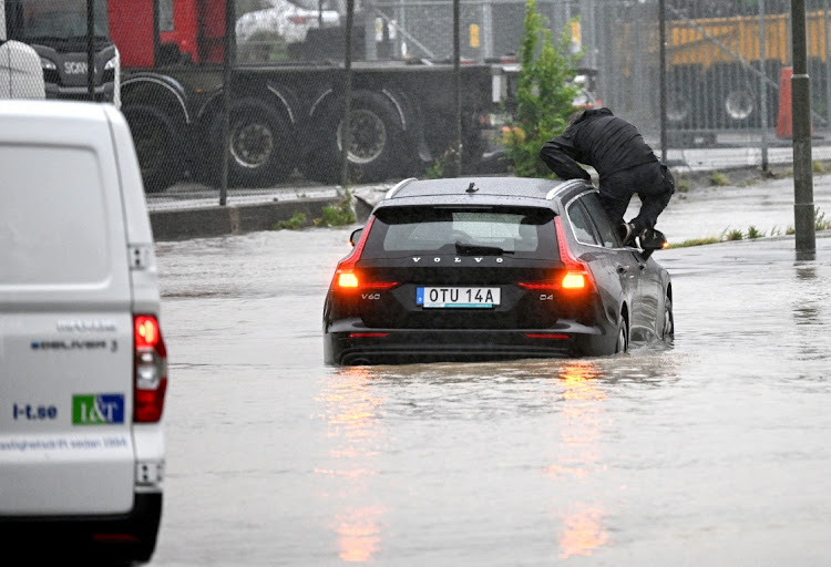 A man climbs out of a car on the flooded E6 outside Malmo, Sweden, August 7 2023. Picture: TT NEWS AGENCY/REUTERS