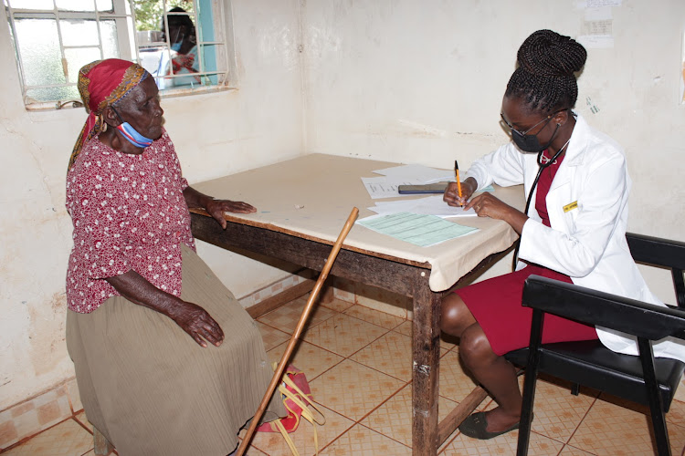 An elderly woman talking to a medic at Kambirwa dispensary in Kiharu constituency.