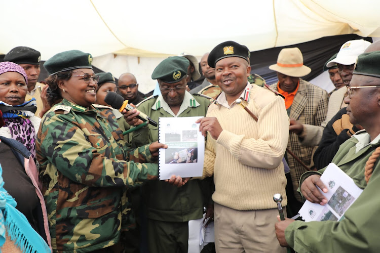 KFS deputy chief conservator of forest Beatrice Mbula with Lari deputy county commissioner Samuel Kariuki handing over copies of FMAs and PFMPs