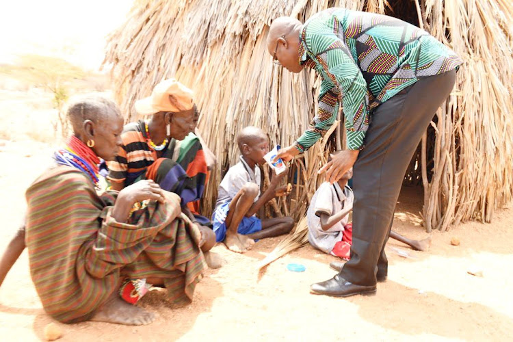 Turkana Governor Jeremiah Lomorukai gives milk to a boy affected by drought on November 3, 2022