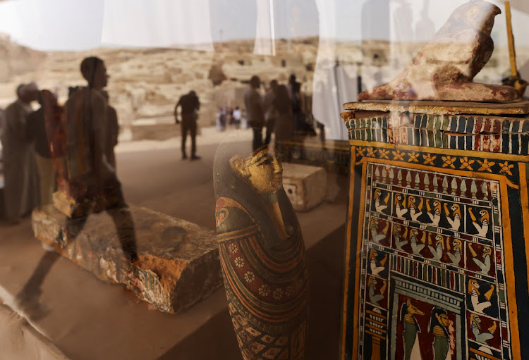 Reflections of people are seen on the unearthed ancient artefacts displayed after a conference to announce the newly discovered site where two embalming workshops for humans and animals along with two tombs and a collection of artefacts were found, near Egypt's Saqqara necropolis, in Giza, Egypt May 27, 2023.