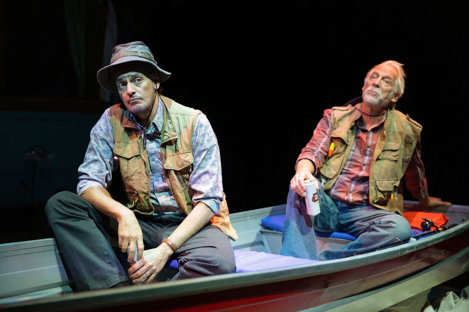 Two men sitting on a boat on stage.