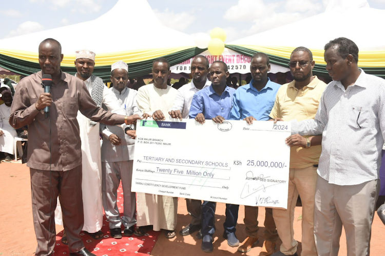 Tarbaj MP Hussein Bare hands over a dummy cheque for Sh25 million to school heads and principals during issuance of bursaries in the constituency, March 23, 2024.