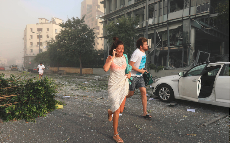 People run for cover following an explosion in Beirut's port area in Lebanon in this file picture. A judge presiding over the matter bomb inquiry has survived attempts to oust him.