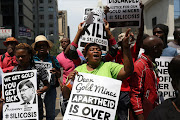 Protesters outside the high court in Johannesburg during the case between gold mining companies and miners who contracted silicosis and TB. An agreement between mineworker representatives and gold mining companies to compensate the workers was made an order of the court. File photo.