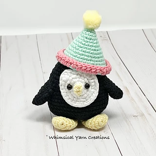 crochet penguin with hat on wooden background