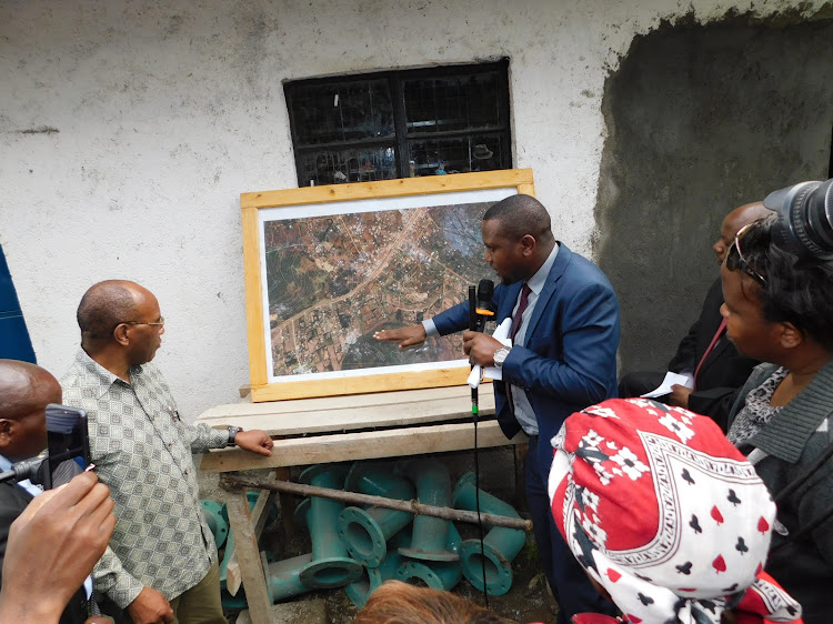 Nyandarua Water executive Simon Ng'ang'a shows Governor Francis Kimemia the map of areas that will benefit from Karago-ini water project in Kiriita, Ndaragwa