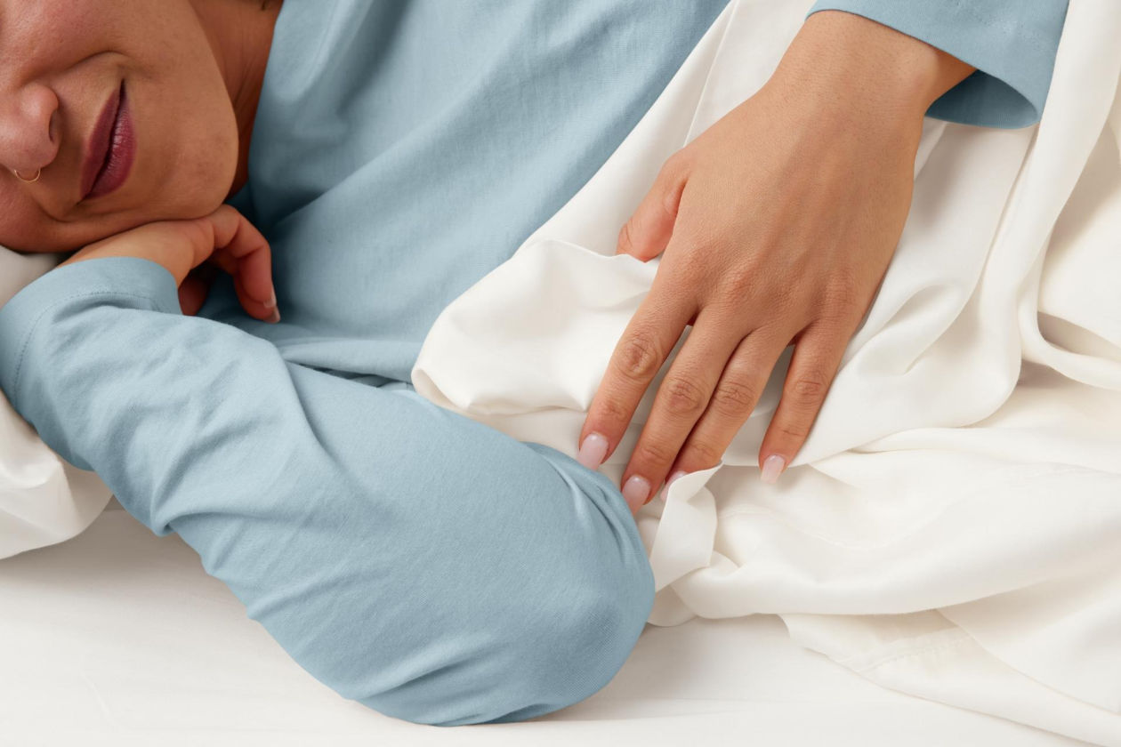 Woman in bed with white sheet.