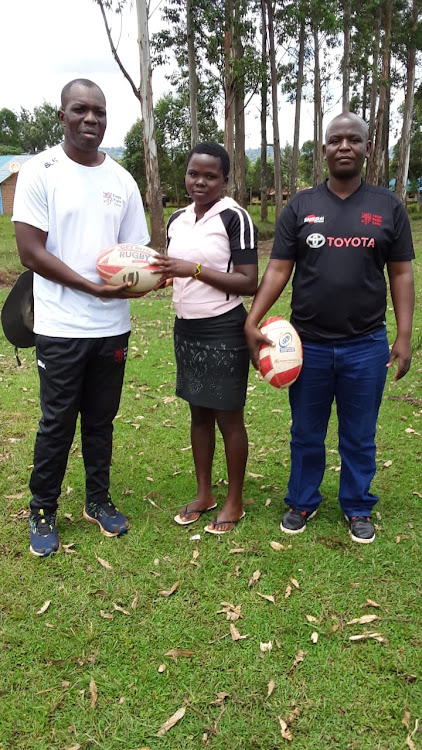 KRU development coordinator Ronald Okoth presents a ball to Martha Oseko at Rianyanchabera secondary. Looking on is Nyanza RDO Joseph Okong'o