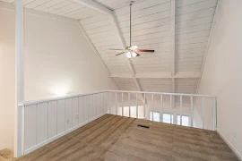 Loft bedroom with brown carpet and white railing