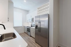 Kitchen with wine rack, stainless steel appliances, modern cabinets, white tile backsplash, and white quartz countertops