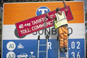 File photo: A worker erects an e-toll tariff  board on the N1 highway between Johannesburg and Pretoria. Photo:   DANIEL BORN