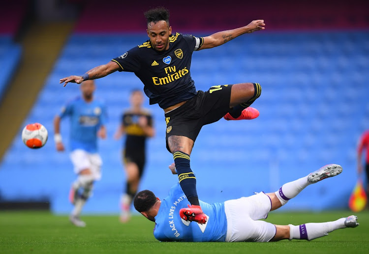 Kyle Walker of Manchester City tackles Pierre-Emerick Aubameyang of Arsenal during the Premier League match between Manchester City and Arsenal FC at Etihad Stadium on June 17, 2020 in Manchester, United Kingdom.