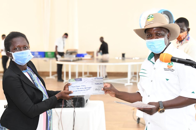 Kisumu Deputy Governor Mathews Owili hands over a cheque to a beneficiary during the micro-projects under the Kenya Climate Smart Agriculture Project launche in Kisumu on Saturday May 16, 2020