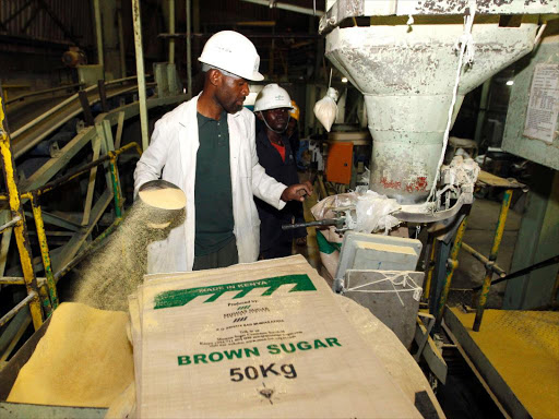 A worker weighs and packs bags of sugar at the Mumias sugar factory in western Kenya February 24, 2015./REUTERS