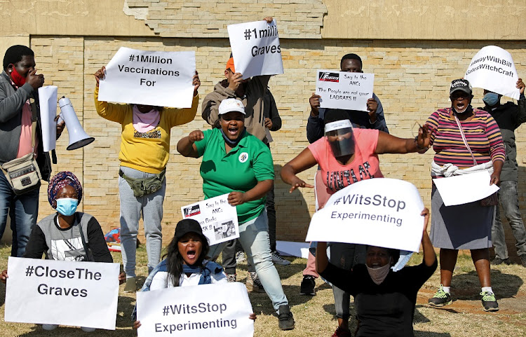 Protesters hold placards during a demonstration against the coronavirus disease (COVID-19) vaccine testing, outside Baragwanath hospital in Soweto, South Africa, July 18, 2020.