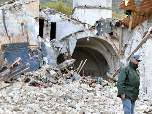 An officer of the State Forestry Corp national police stands in front of a collapsed church in Campi di Norcia, central Italy, October 27, 2016. /REUTERS