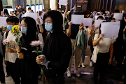 People hold white sheets of paper in protest over coronavirus disease (Covid-19) restrictions in mainland China, during a commemoration of the victims of a fire in Urumqi, in Hong Kong, China on November 28, 2022. 
