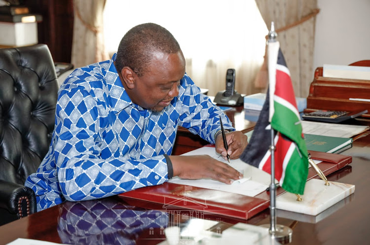 President Uhuru Kenyatta signs a Bill into law at Sate House, Nairobi.