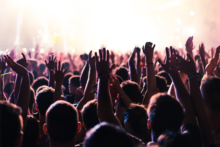 Happy shiny people: Audience with hands raised at a music festival and lights streaming down from above. Picture BERNARD BODO/123RF