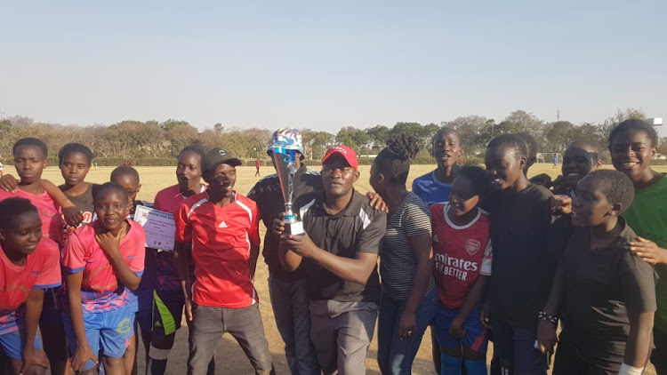 Moi Girls' Eldoret head coach Robert Simiyu holds the trophy after winning the Nakuru Open