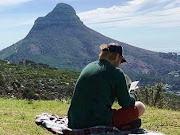 Ed Sheeran reads a book on Table Mountain on March 26 2019.