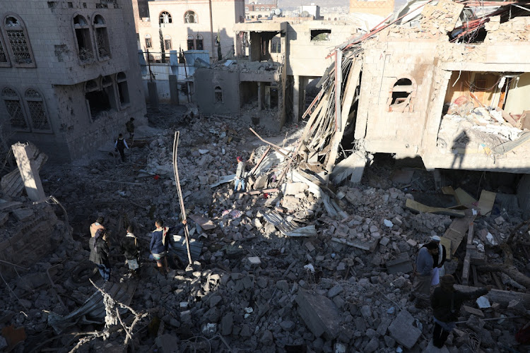 People stand at the site of Saudi-led air strikes in Sanaa, Yemen, January 18, 2022.