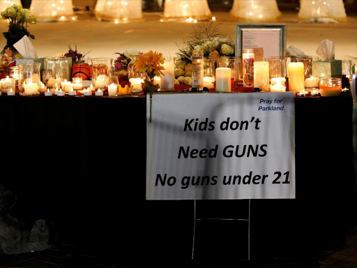 A sign is seen next to candles and tributes at a park where crosses were placed to commemorate the victims of the shooting at Marjory Stoneman Douglas High School, in Parkland, Florida, US, February 16, 2018. /REUTERS